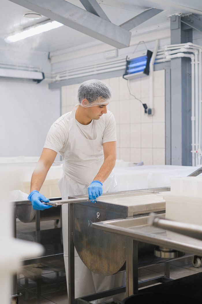 services-01 Man in a protective suit managing machinery in a dairy processing facility.